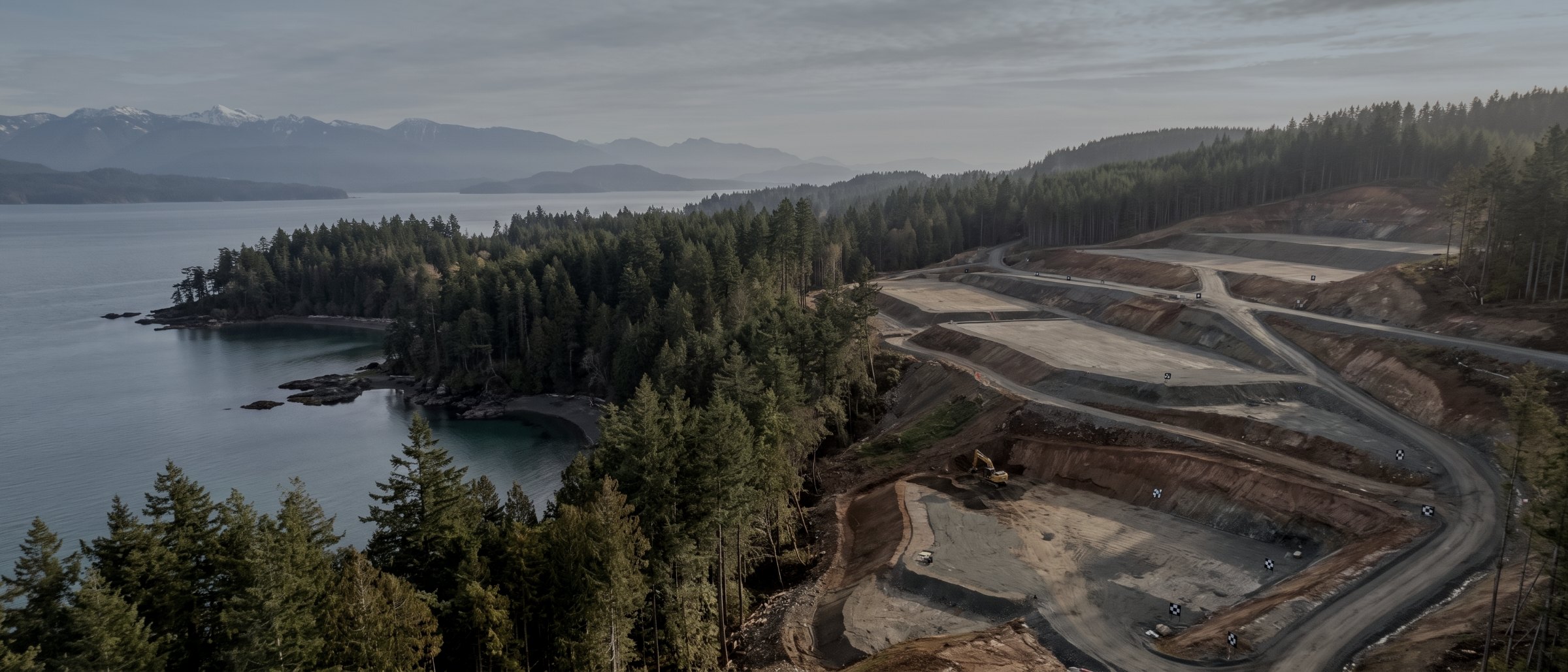 Aerial view of a large coastal earthworks site with graded pads and benched roads